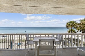 A balcony with a table and chairs overlooking a beach. - Corner Retreat with Gulf & Intracoastal Views from Wraparound Balcony at Fifty Gulfside (Indian Rocks Beach)