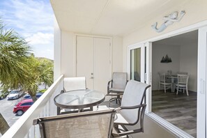 A balcony with a glass door leading to a dining area, furnished with chairs and a table.