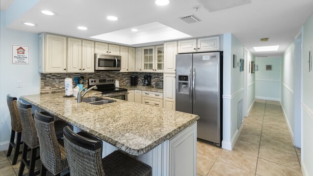 Una cocina moderna con encimeras de granito, electrodomésticos de acero inoxidable y muebles de color azul claro.