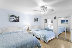 Ein Schlafzimmer mit zwei Betten, einem Deckenventilator und einem großen Spiegel.