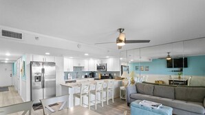 Una cocina moderna con armarios blancos, un refrigerador de acero inoxidable y una isla central con taburetes de bar.