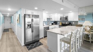 Una cocina moderna con armarios blancos, electrodomésticos de acero inoxidable y una isla de mármol.