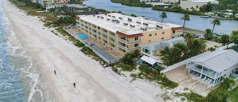 An aerial view of a beachfront hotel with multiple buildings, a swimming pool, and a river nearby.