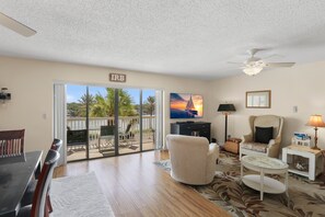 A living room with a view of a body of water, a ceiling fan, and a television.