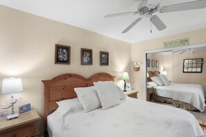 A hotel room with a bed, a nightstand, a lamp, a ceiling fan, and framed pictures on the wall. - 🌴 Intracoastal Views & Beachside Comfort – Spacious 2BR Condo 2BR/2BA Sleeps 4 Fifty Gulfside (Indian Rocks Beach)