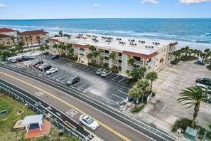 Ein Hotel direkt am Strand mit Parkplatz, einer Straße mit Radweg und Blick auf das Meer.