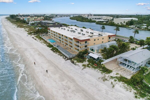 Eine Luftaufnahme eines Strandhotels mit mehreren Gebäuden, einem Schwimmbad und einem Fluss in der Nähe.