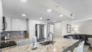 A modern kitchen with a marble countertop, stainless steel appliances, and a built-in sink.