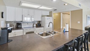 Een moderne keuken met witte kasten, roestvrijstalen apparatuur en een groot eiland met een spoelbak.
