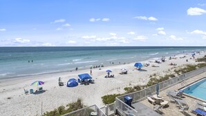 Een strand met parasols, ligbedden en een zwembad.
