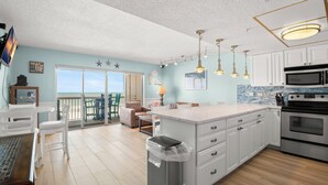 Une cuisine moderne avec des meubles blancs, un grand îlot central et une vue sur l’extérieur.