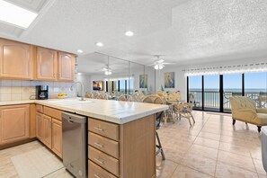 A spacious kitchen with a large island, wooden cabinets, and a dishwasher. - Panoramic Gulf Views – Spacious 2BR Condo at Fifty Gulfside Unit #316  2BR/2BA  Sleeps 6 (Indian Rocks Beach)
