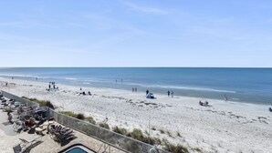 Ein Strand mit Poolbereich, Sonnenschirmen und Liegestühlen.
