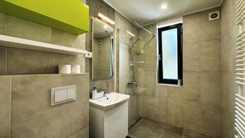 Un bagno moderno con doccia, lavabo e finestra.
