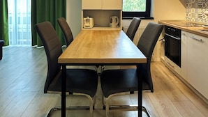 A modern kitchen with a wooden dining table, black chairs, and a window with a view of greenery. - Timisoara Prime Residence | powered by NEO (Timisoara)