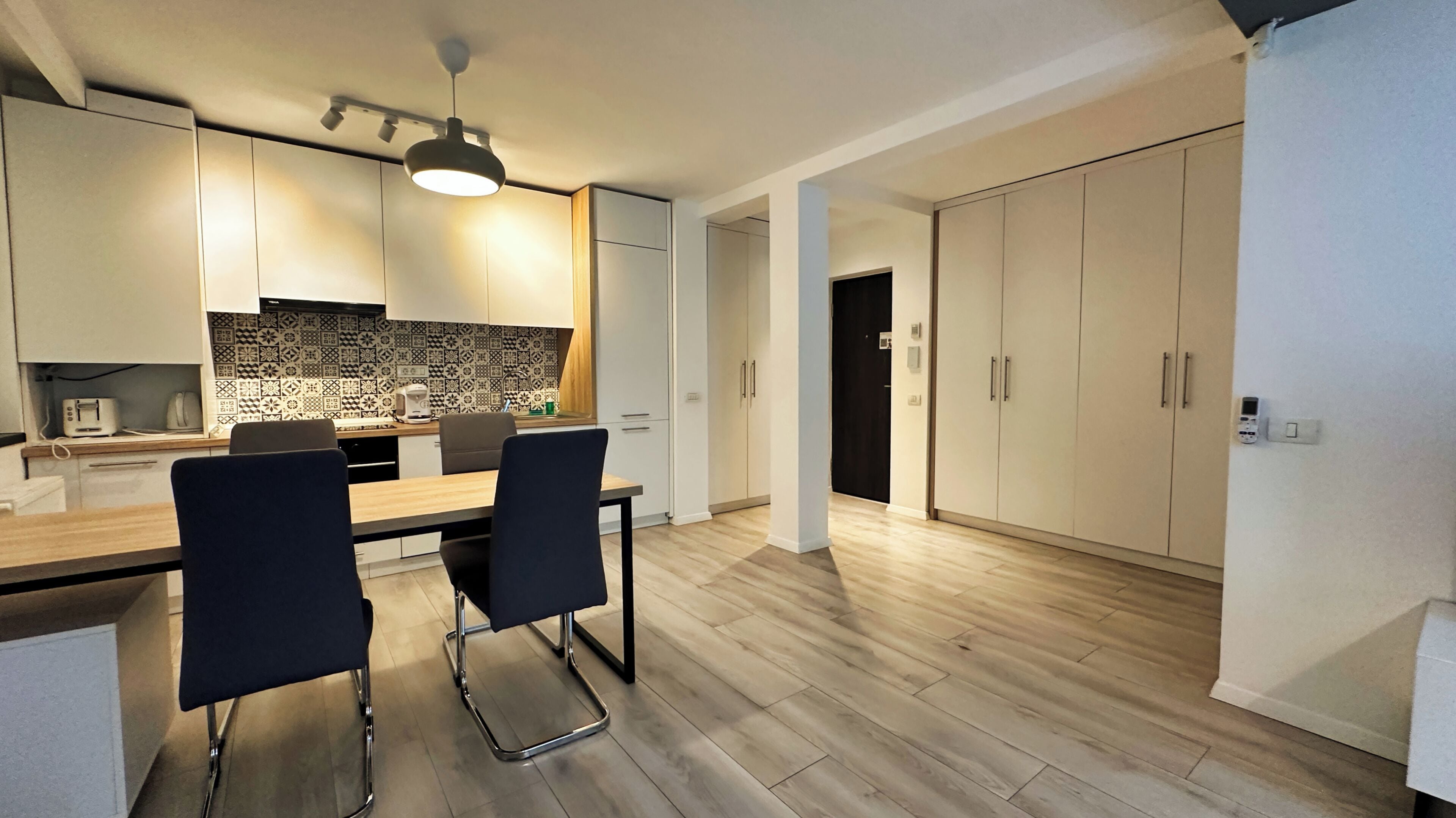 Une cuisine moderne avec un coin repas, comprenant une table en bois, deux chaises et un crédence décorée.