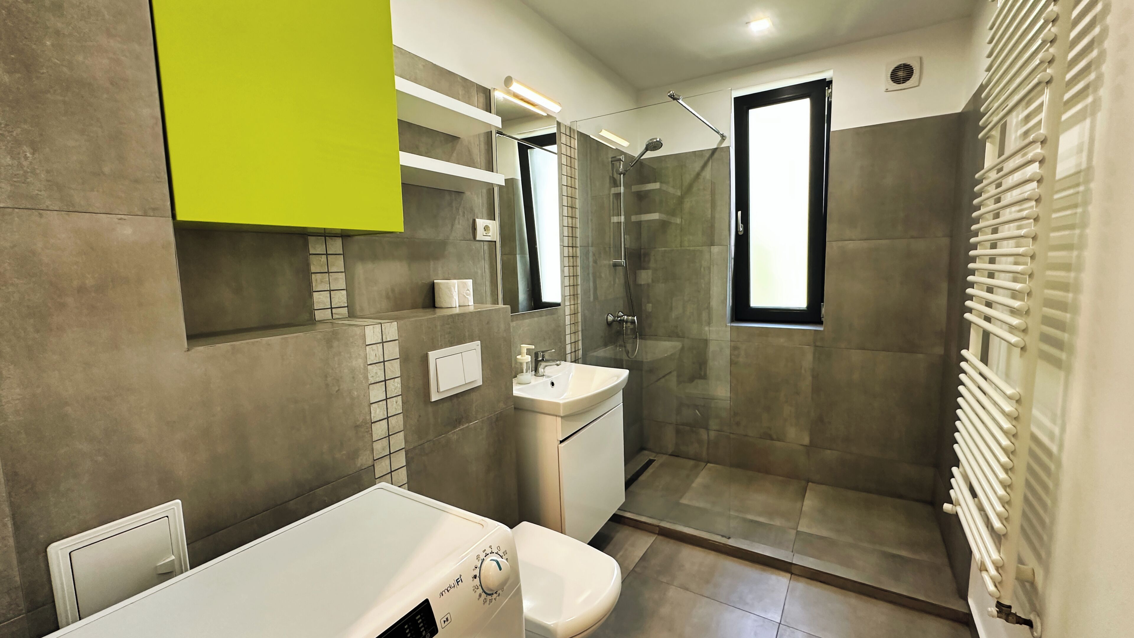 Een moderne badkamer met een douchecabine van glas, een wit wastafelmeubel en een toilet.