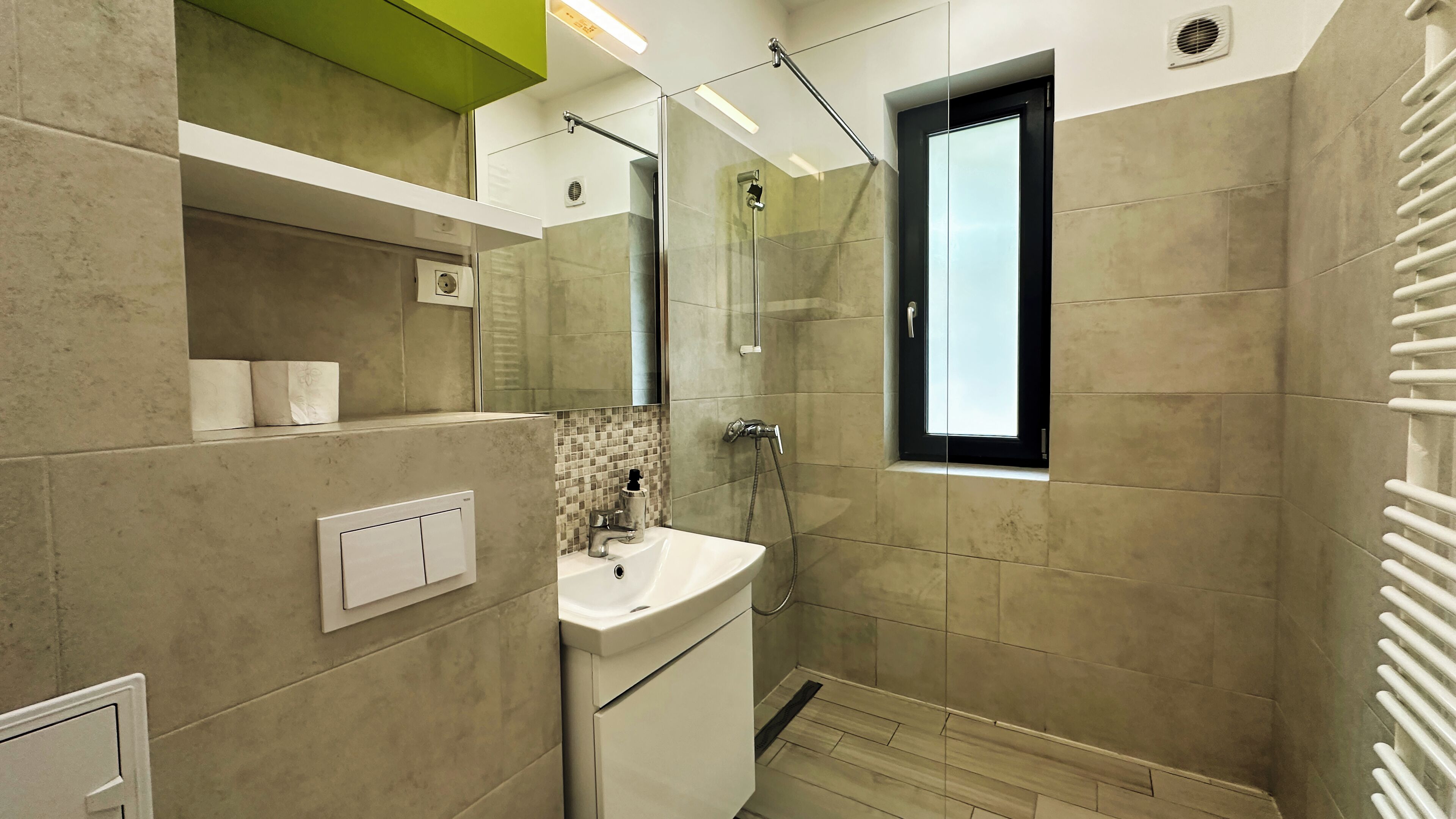 Un baño moderno con cabina de ducha de vidrio, un lavabo con espejo y una ventana.