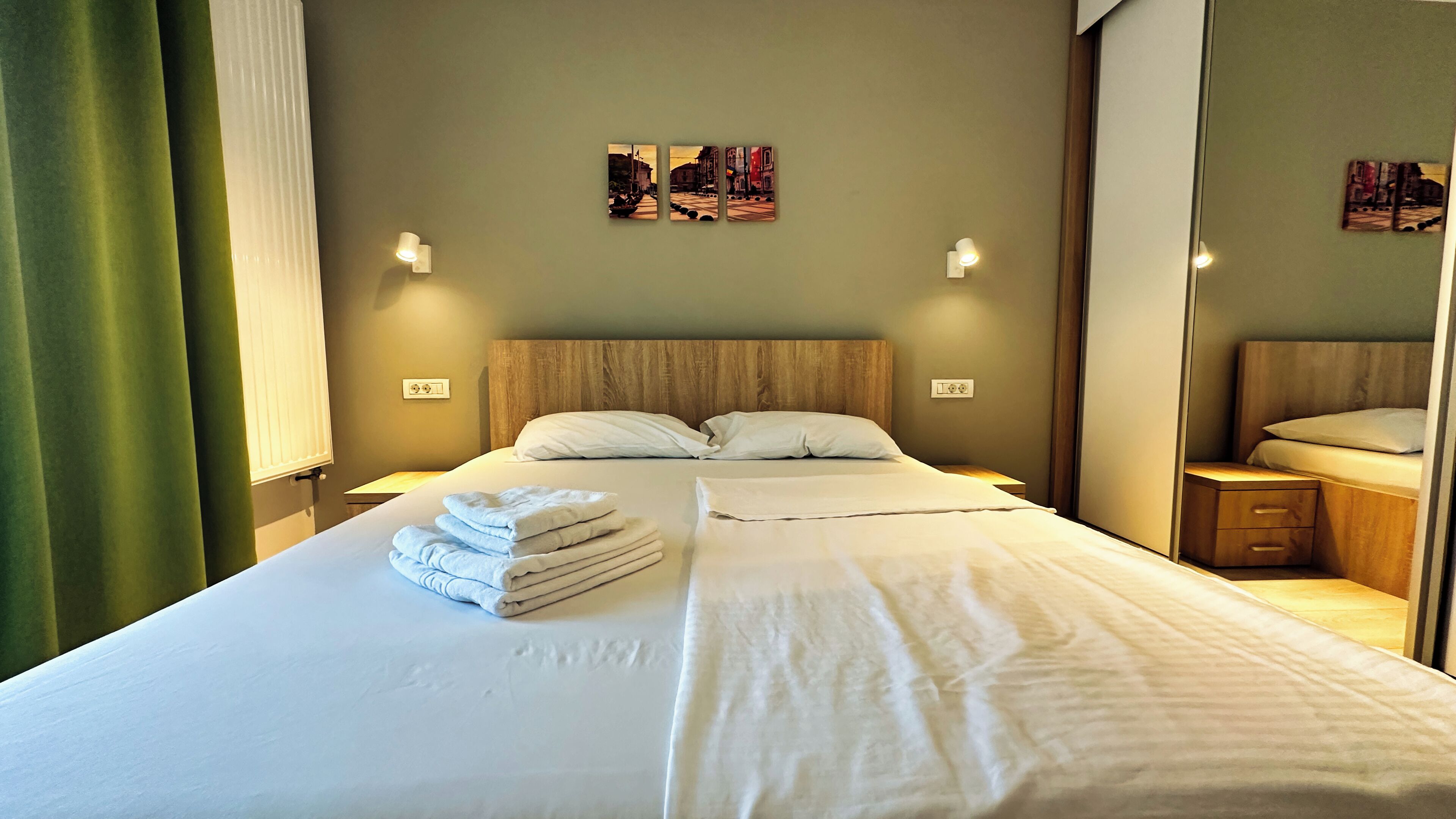 A hotel room with a large bed, two bedside tables, a nightstand, and a mirror.