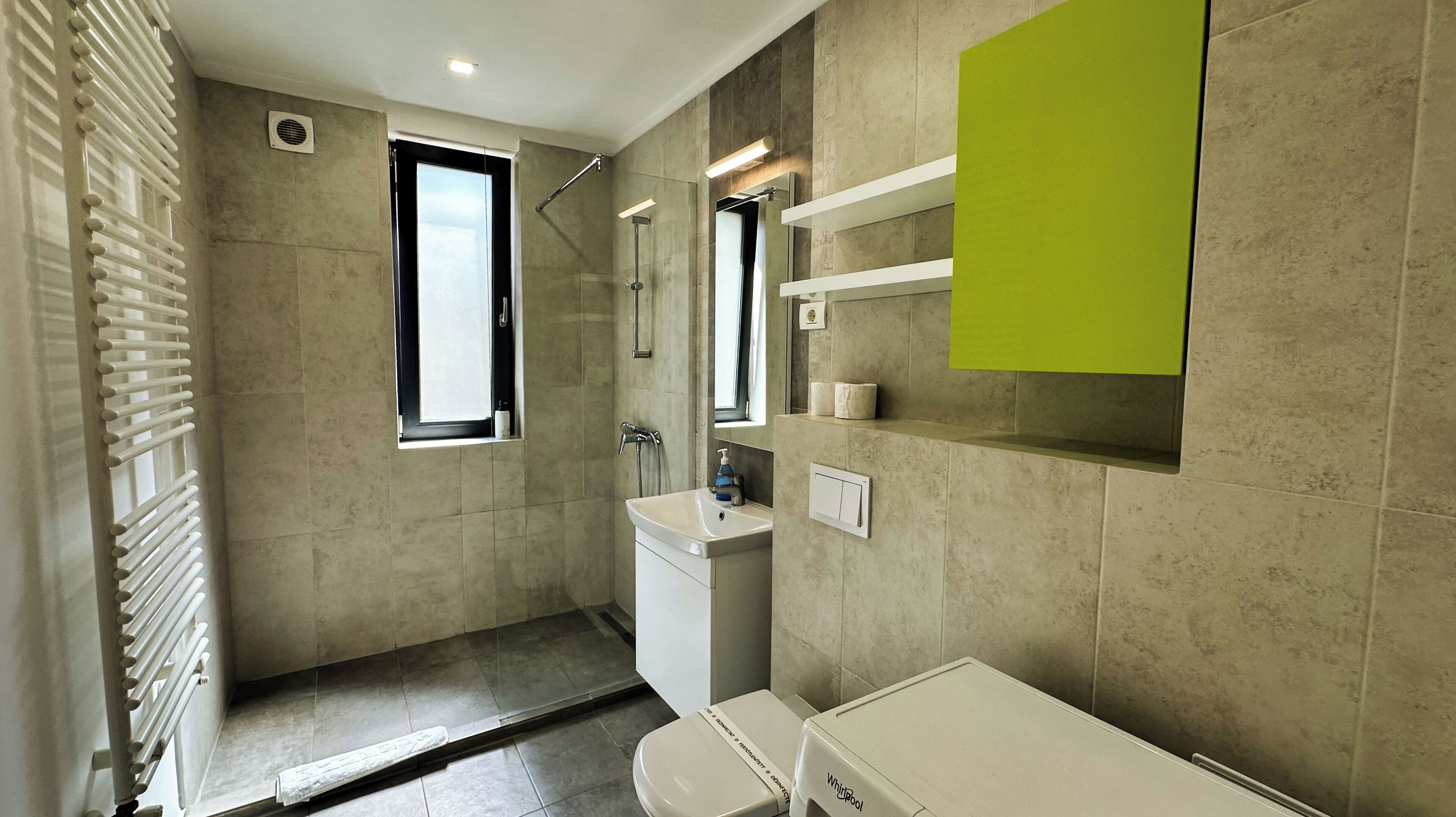 A modern bathroom with a shower, toilet, and sink.