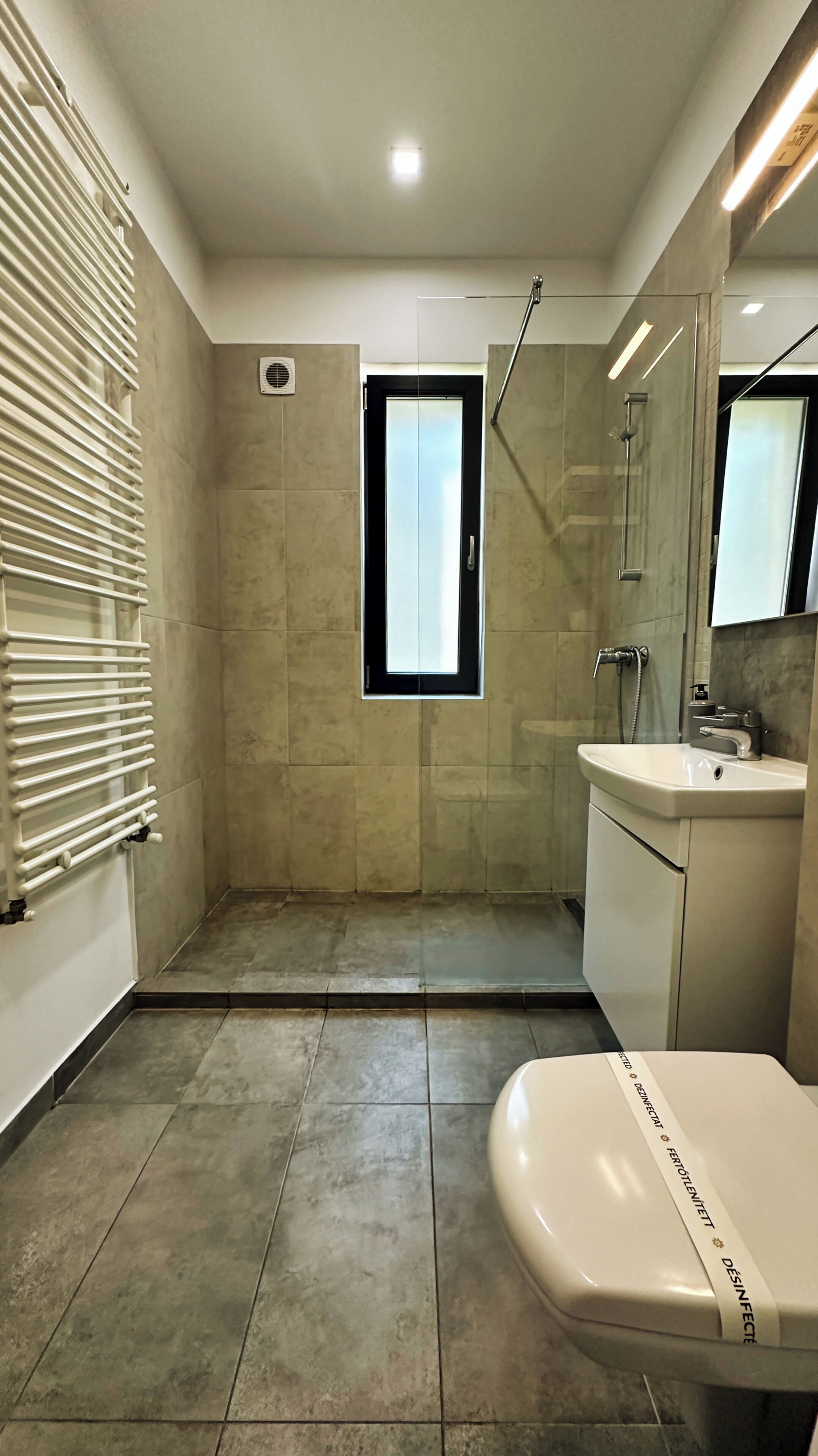 A modern bathroom with a shower, a toilet, and a sink.