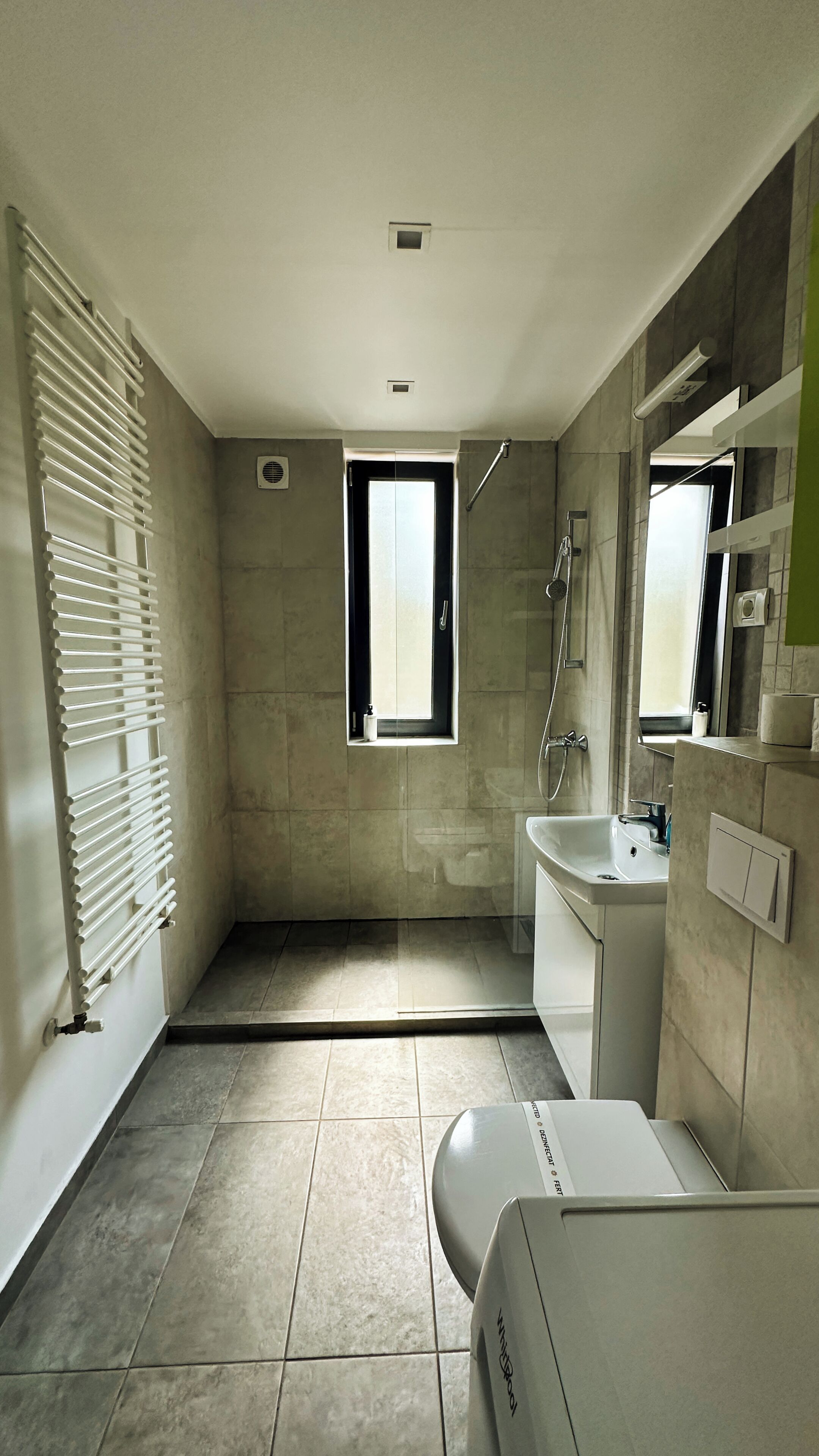 A modern bathroom with a shower, toilet, and sink.