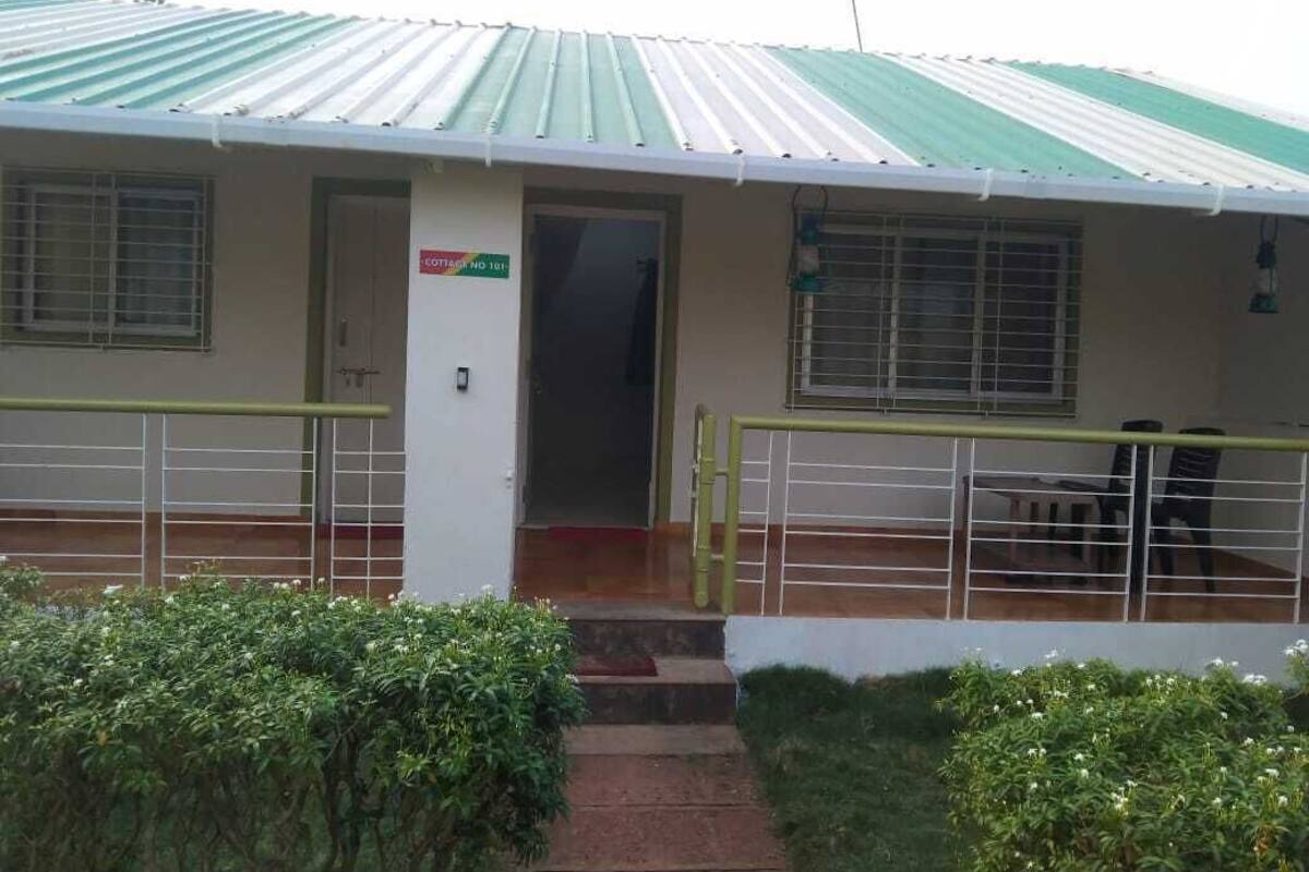A building with a green and white roof, a sign reading "COTTAGE NO 1", and a staircase leading to a door.
