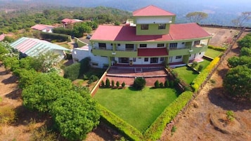 A large, multi-story building with a red roof, surrounded by well-maintained lawns and gardens.