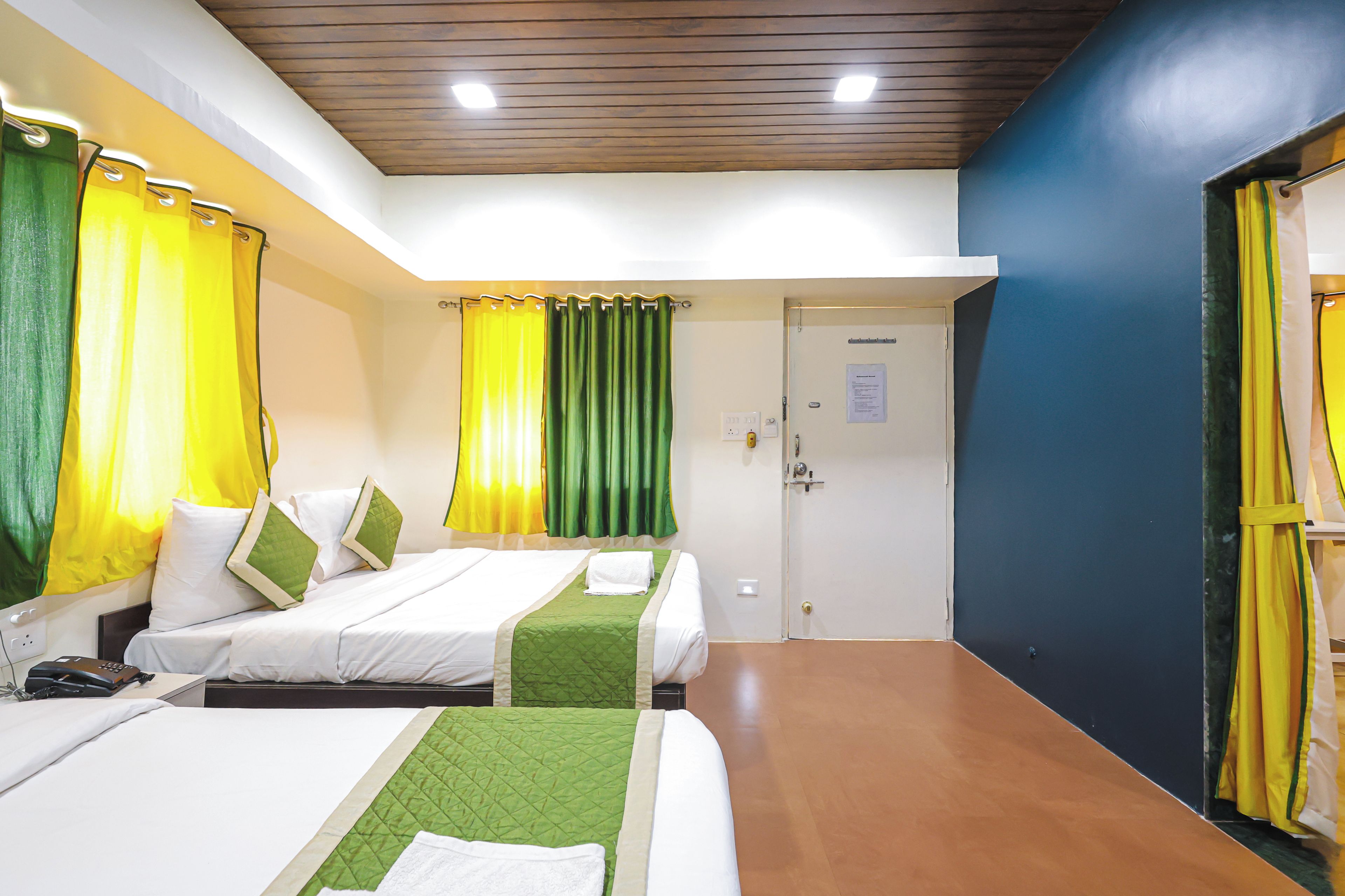 A hotel room with two beds, a wooden ceiling, and a door with a notice on it.