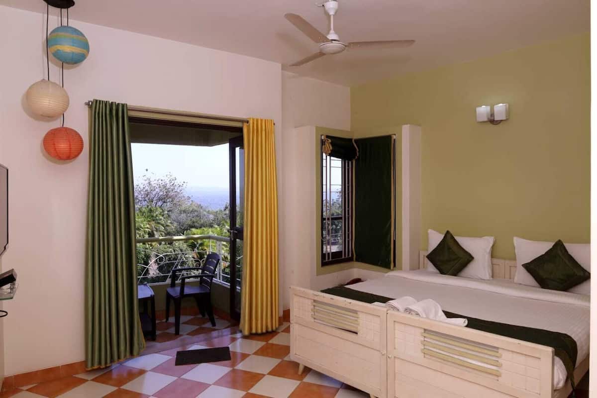 A bedroom with a bed, a window, a ceiling fan, and a balcony with a chair.