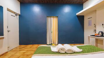 A hotel room with a bed, a desk, a shower curtain, and a wooden ceiling.