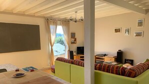 Een gezellige woonkamer met een groene bank, een houten tafel en een televisie.