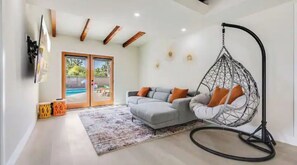 Relax in this stylish living room with a sofa, hanging chair, and flat-screen TV.