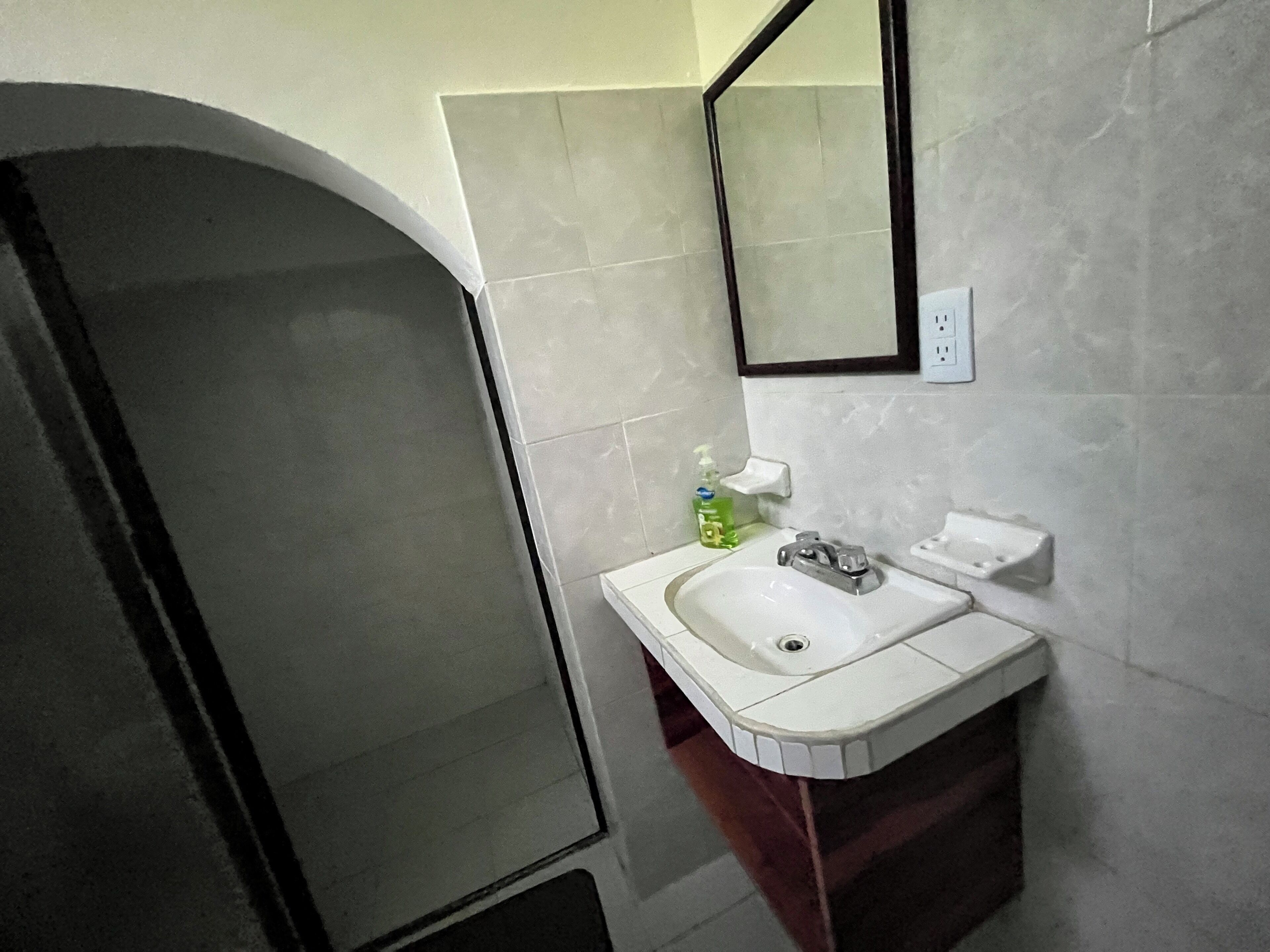 A bathroom with a white sink, a mirror, and a shower area.