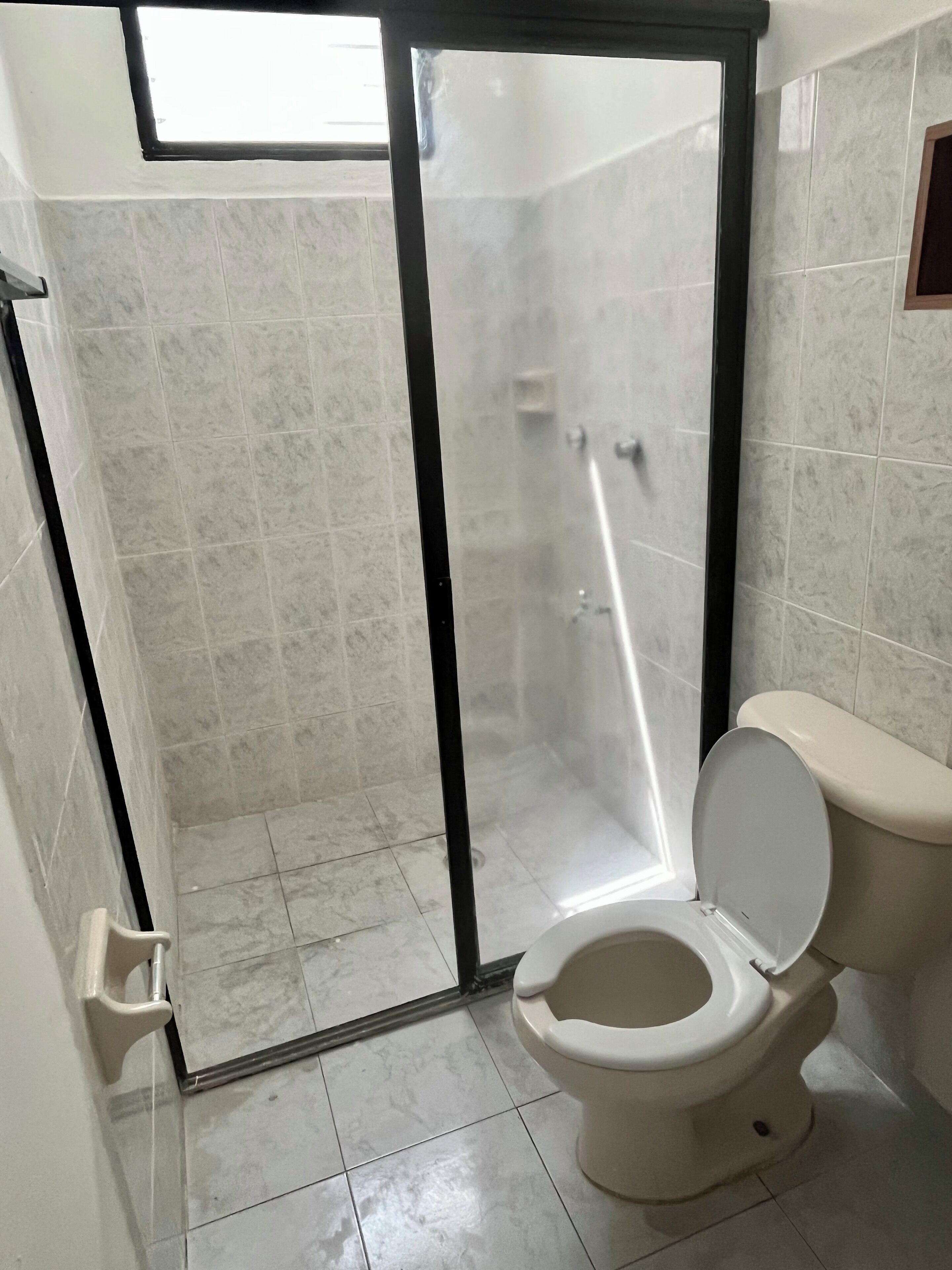 A bathroom with a toilet, a shower enclosure, and tiled walls.