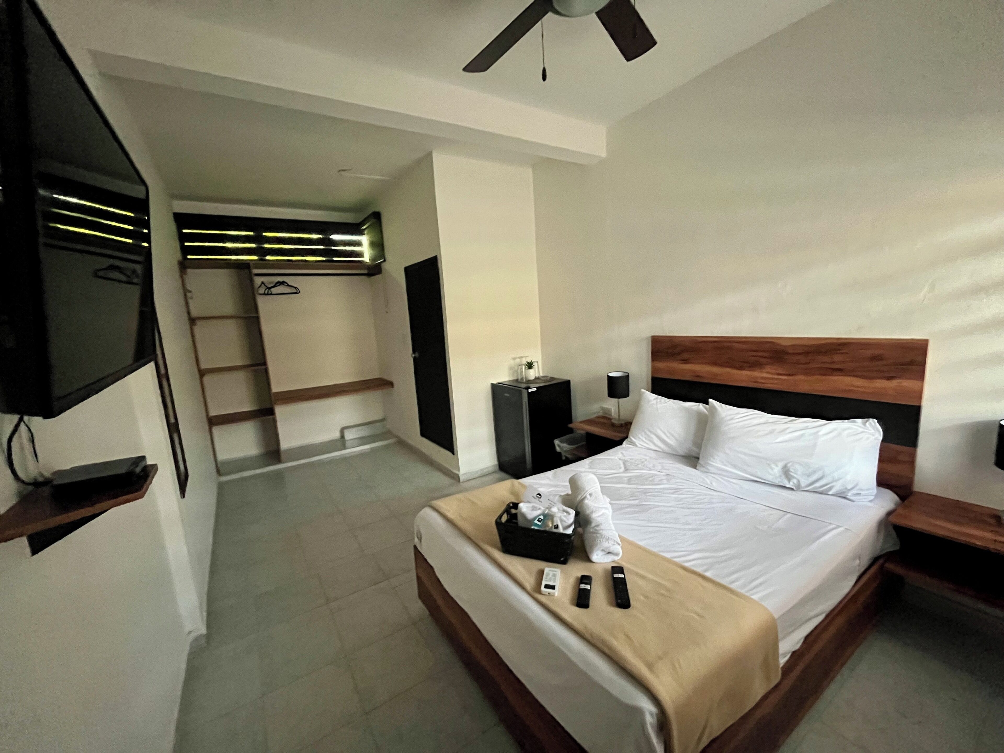 Une chambre d’hôtel comprenant un lit, des tables de chevet, une télévision, un bureau et une armoire.