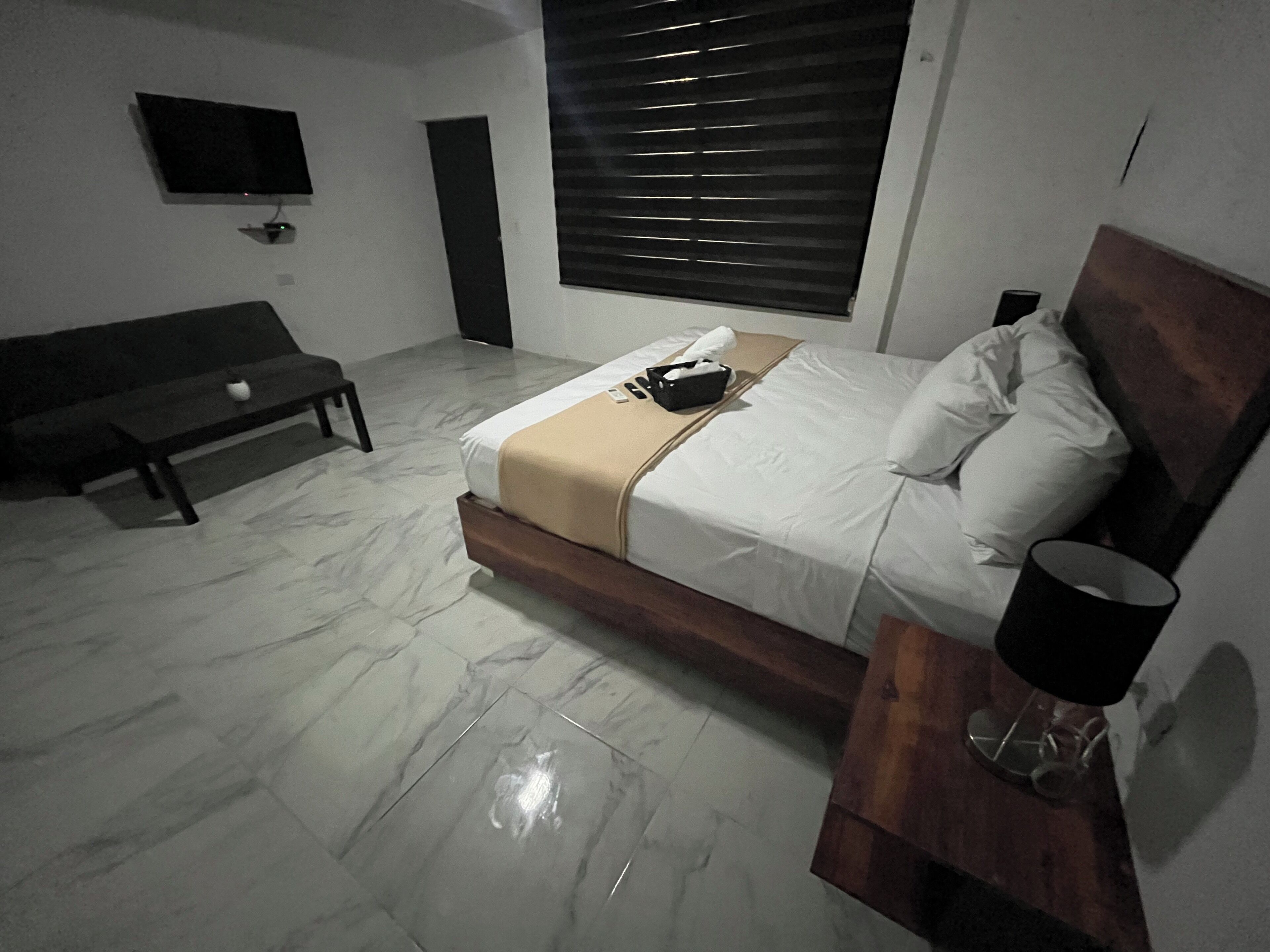 Un dormitorio con cama, mesita de noche y un banco.
