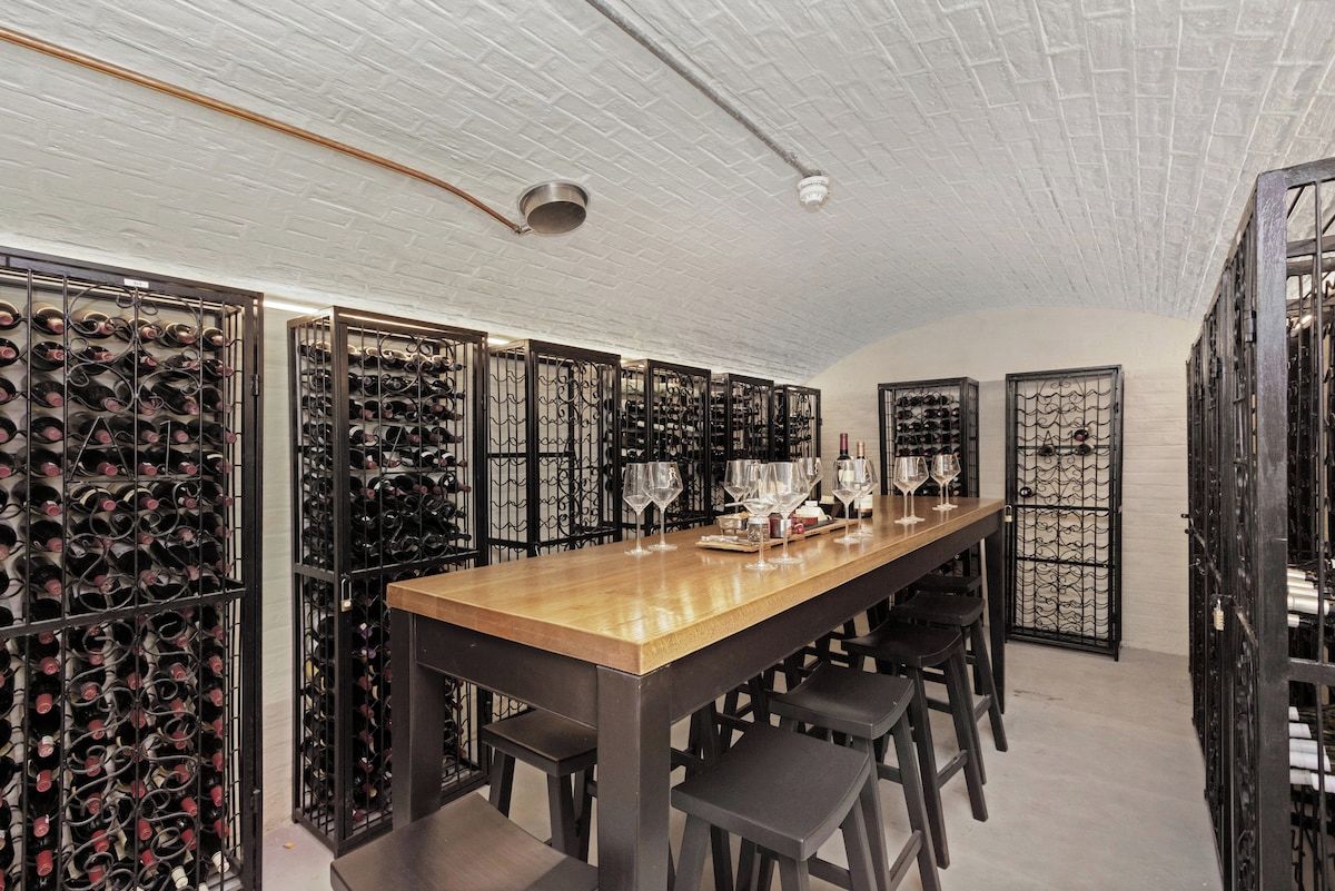 A wine cellar with a long wooden table and multiple wine racks.