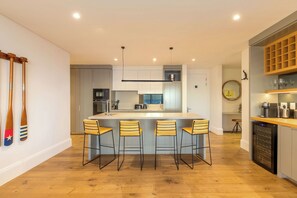 A modern kitchen with a central island, bar stools, and a wine rack. - Luxury Sea Point Pad with Ocean balcony views (Cape Town)