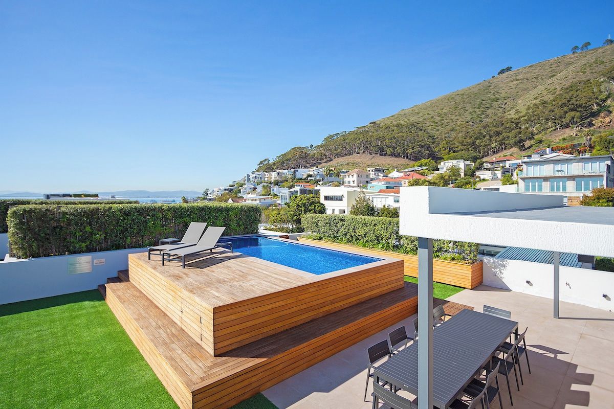 Une piscine sur le toit, avec une terrasse en bois et une vue sur une ville située sur une colline.