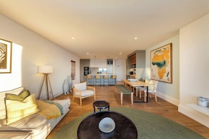 A modern living room with a sofa, a coffee table, and a dining area with chairs.
