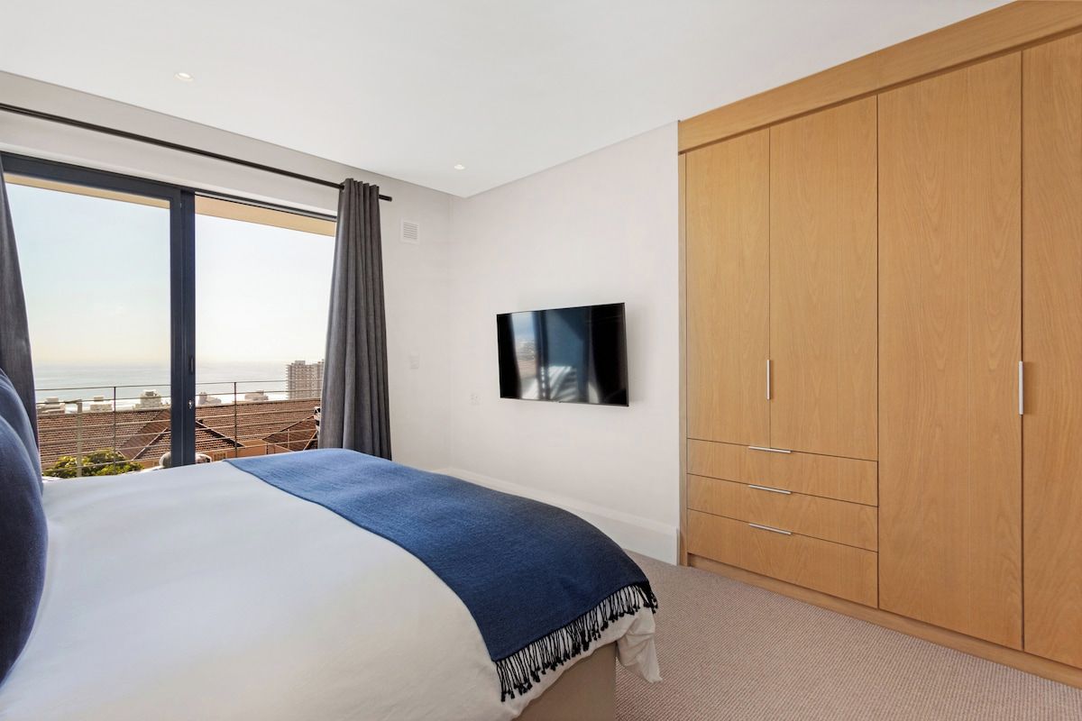 A bedroom with a large bed, a television, and a wardrobe.