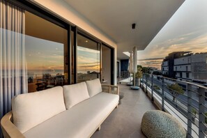 A balcony with a sofa, a potted plant, and a view of the cityscape.