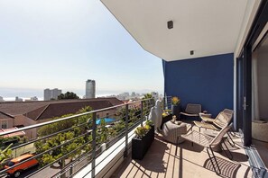 Un balcón con vistas a la ciudad, mobiliario exterior y barandilla.