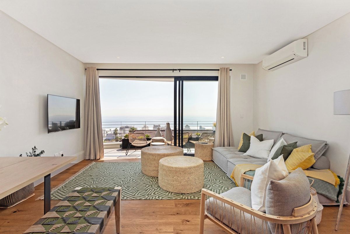 A modern living room with a balcony, a sofa set, a coffee table, and a TV mounted on the wall.