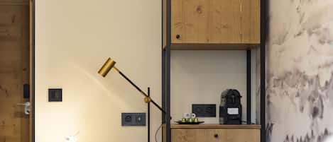 Un espacio de trabajo funcional con escritorio, silla, lámpara y cafetera.