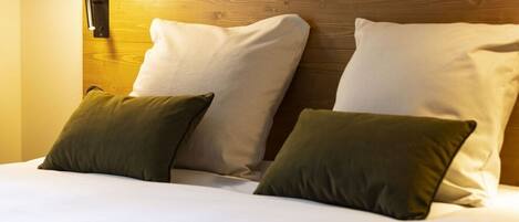 A hotel room with a wooden headboard, two white pillows, and a green pillow.