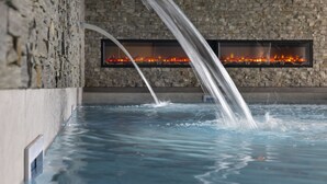 A spa area with a stone wall and a fire feature. - Higalik Hotel (Les Belleville)