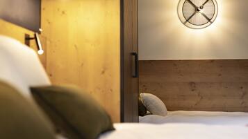 A bedroom with a wooden headboard, a round wall-mounted light fixture, and a bed with white bedding and pillows.