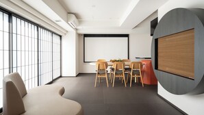 A modern conference room with a large screen, a round table, and several chairs. - MIMARU Osaka Shinsaibashi North (Osaka)